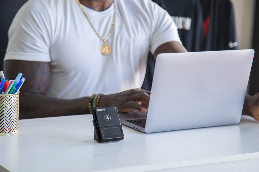 A business owner on their laptop at the front desk. On the desk are items needed to run a business such as a credit card reader.